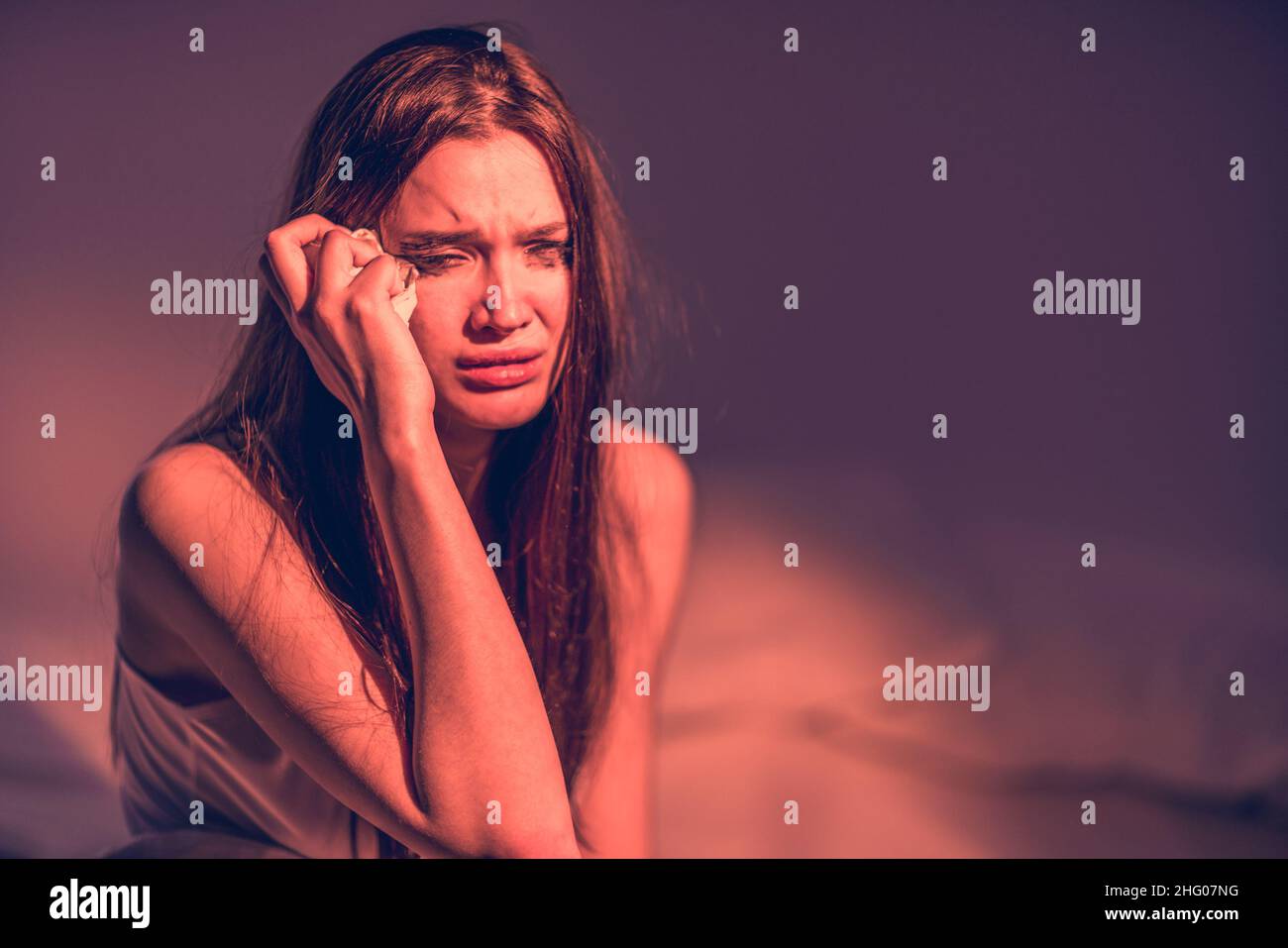 Get upset. Get the bad news. To suffer. Broken heart. Depression. A woman with a face dirty from mascara sits in bed, cries, wipes away her tears. Hea Stock Photo