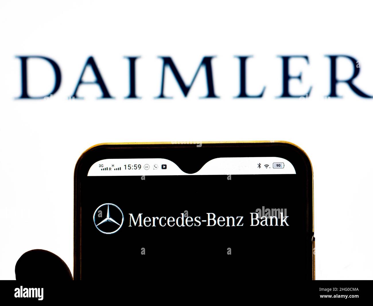 In this photo illustration, the Mercedes-Benz Bank logo is seen displayed on a smartphone screen with the Daimler AG logo in the background. Stock Photo