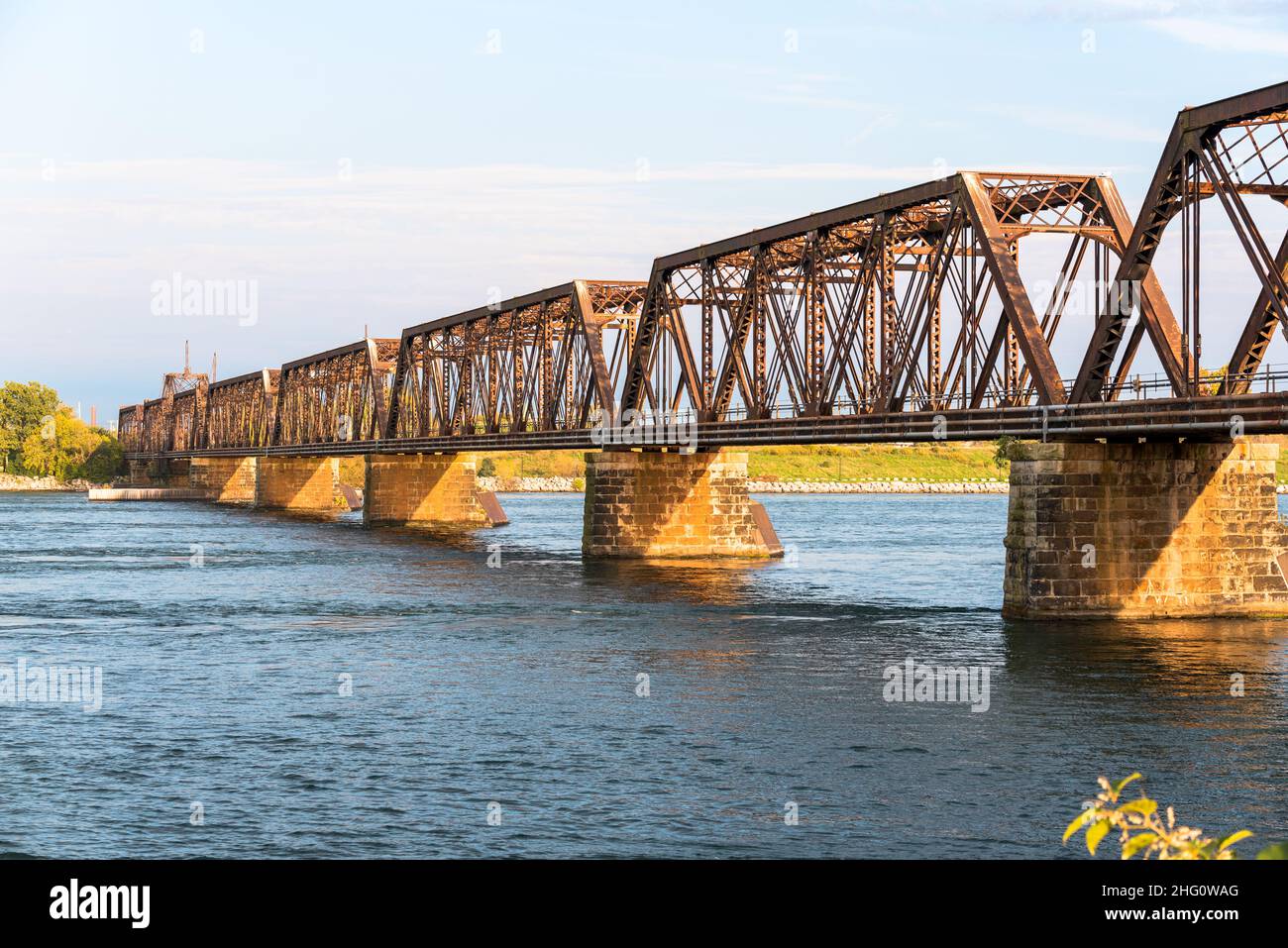 Old Steel railroad bridge spanning a river on a sunny autumn day Stock Photo