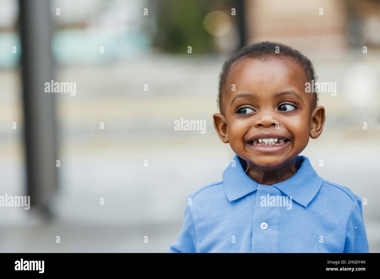 A cute one year old toddler almost preschool age African-American boy with big eyes smiling and looking away with copy space Stock Photo