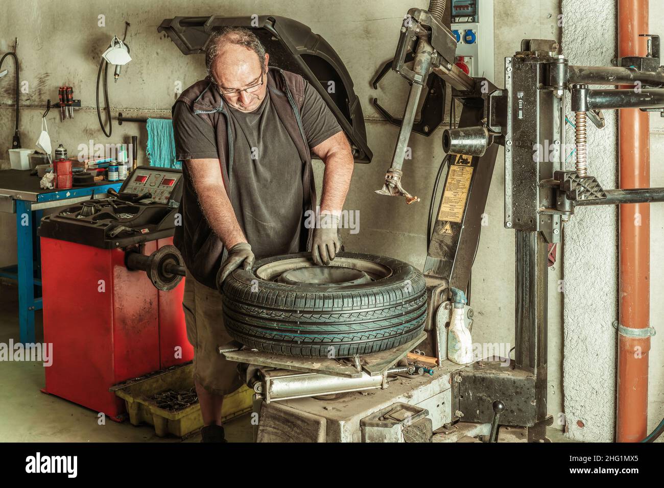 Man standing in a mechanic workshop while repairing a wheel Stock Photo ...