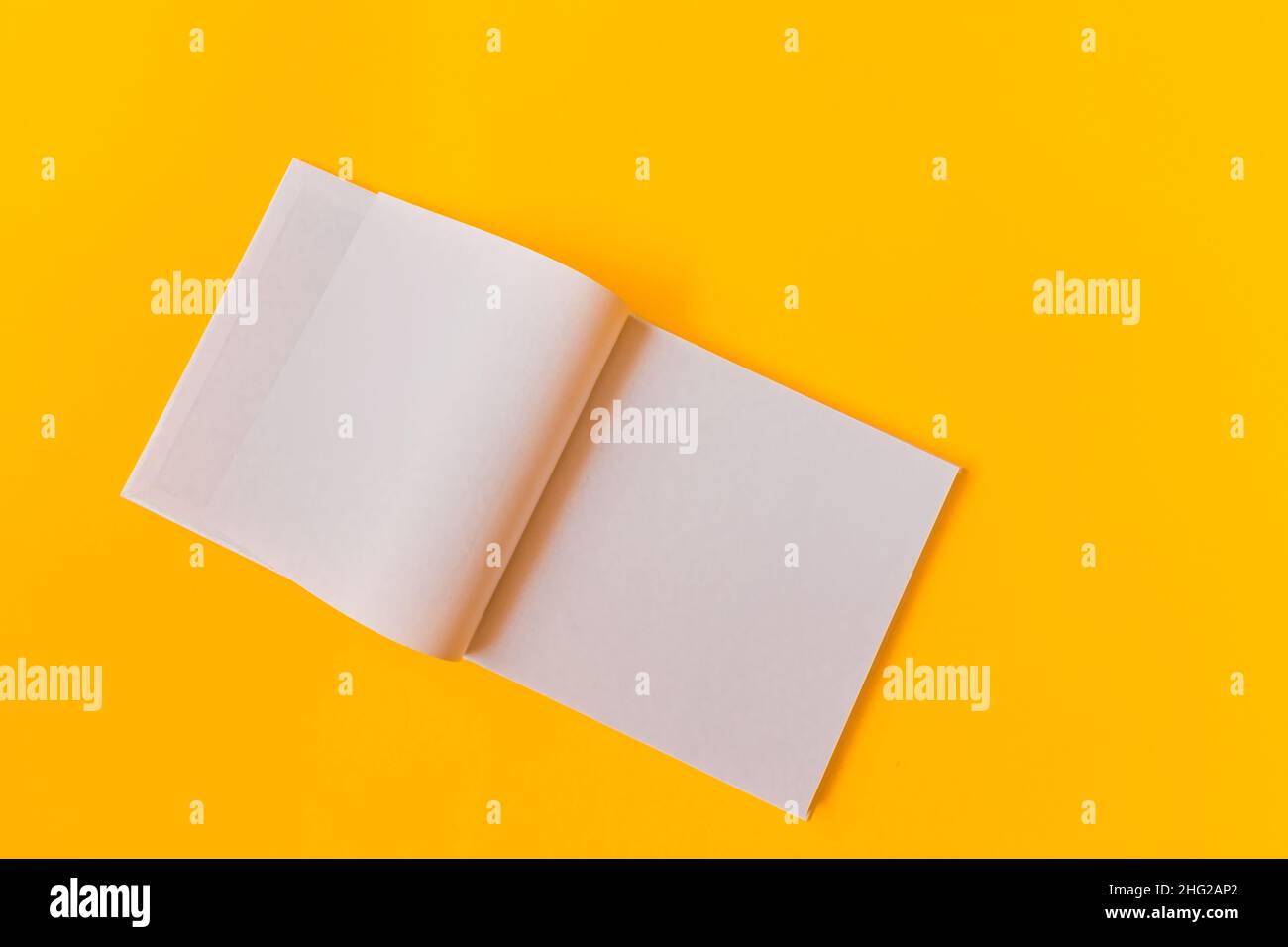 Notebook with white blank pages for notes on a yellow background. Stock Photo