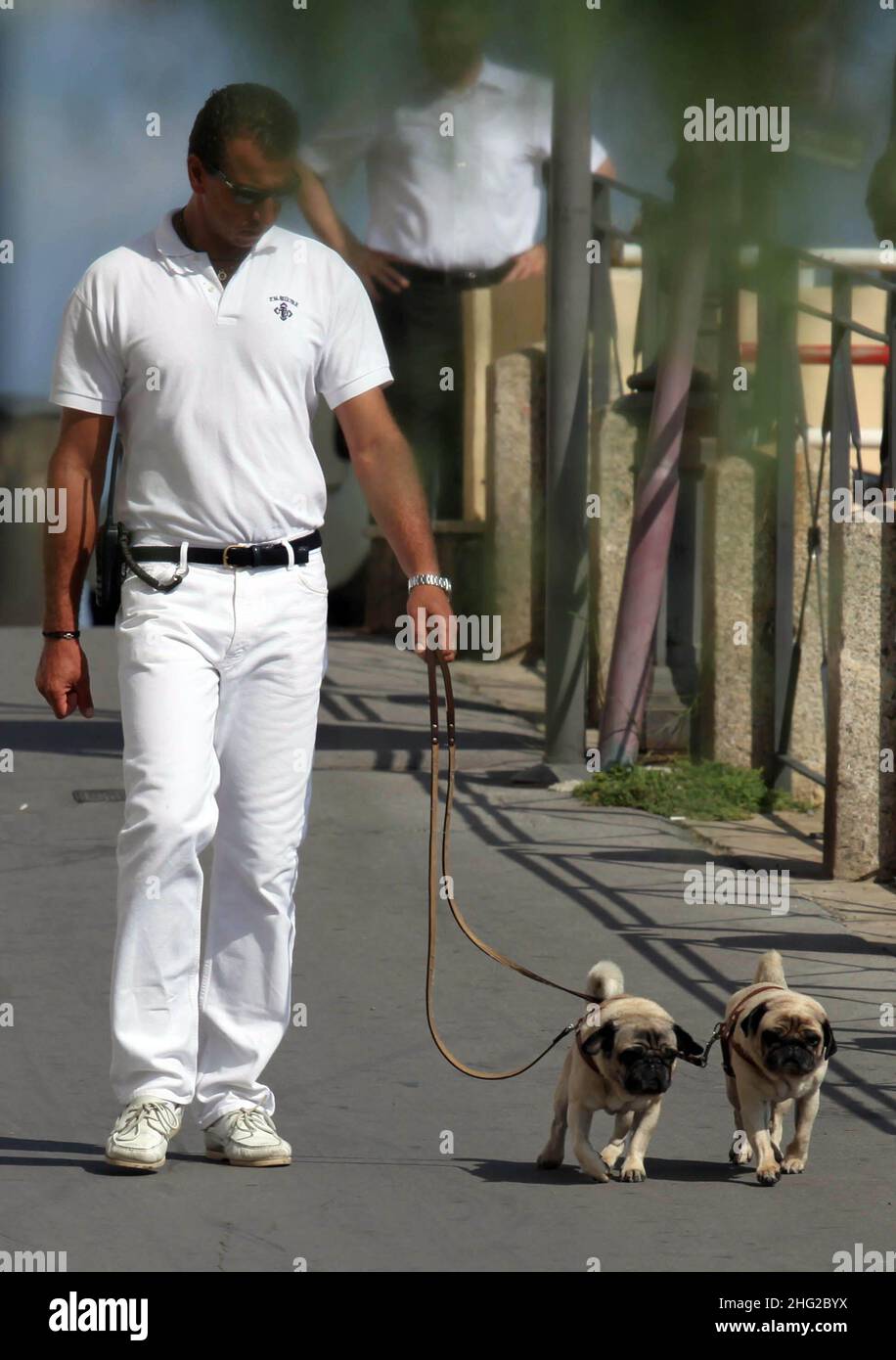 EXCLUSIVE PICTURES. An assistant takes Italian stylist Valentino's dogs for a walk near his yacht in Porto Santo Stefano, Tuscany, Italy. Stock Photo