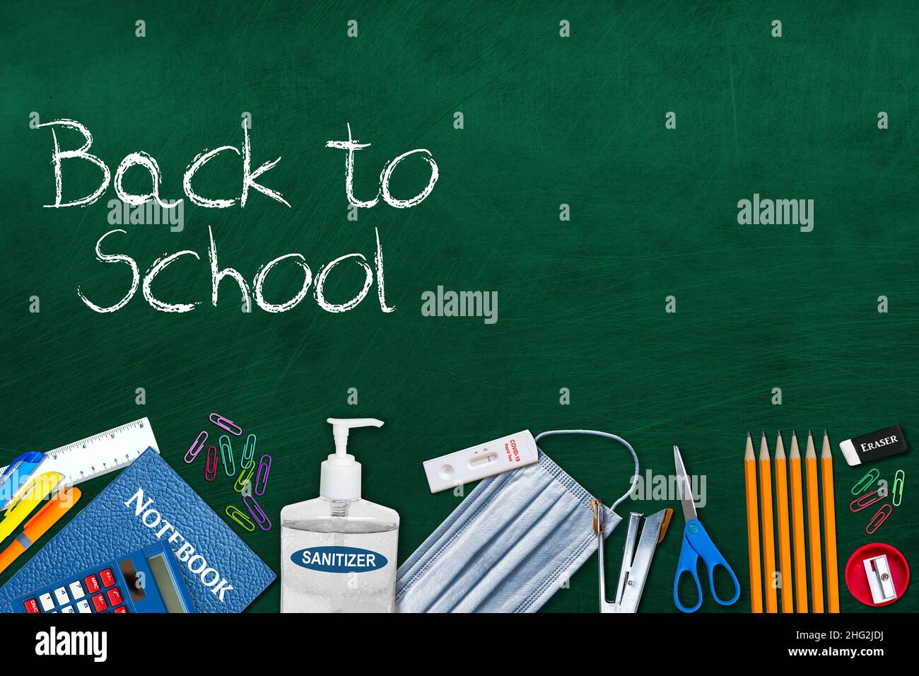 Back to school essentials concept in the new normal during Covid-19 pandemic with rapid test kit, hand sanitizer, face mask and stationery on chalkboa Stock Photo
