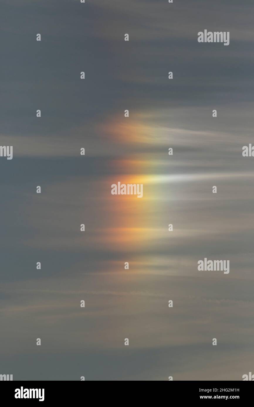 A rainbow-like Sun Pillar consists of ice crystals and is an unusual atmospheric reflection at sunset in California's San Joaquin Valley. Stock Photo