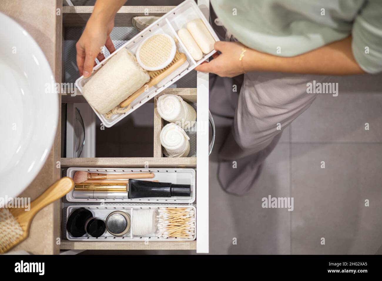 Top view of woman hands neatly organizing bathroom amenities and