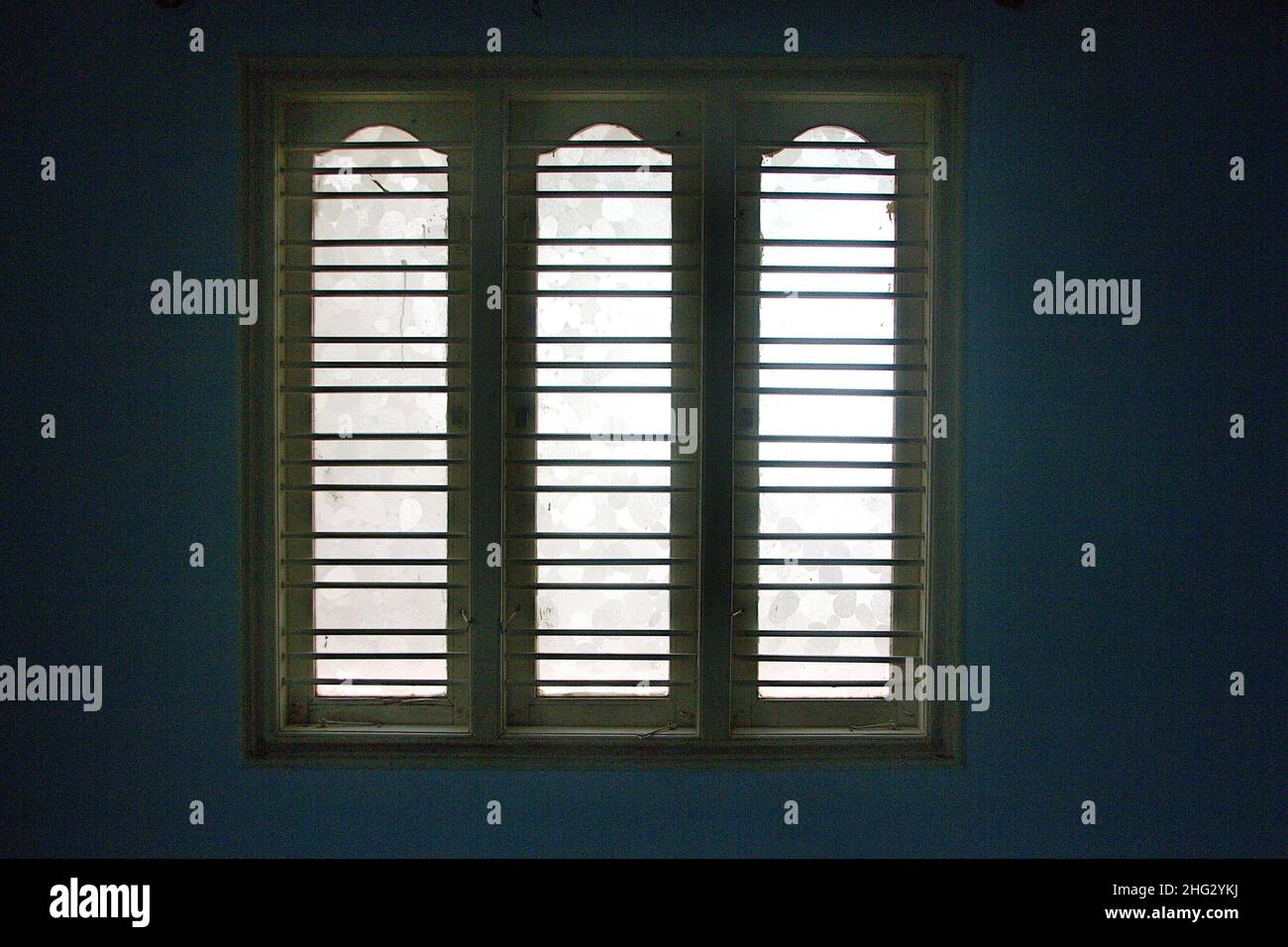 Wooden window frame with safety bars and glass panels viewed from inside room Stock Photo
