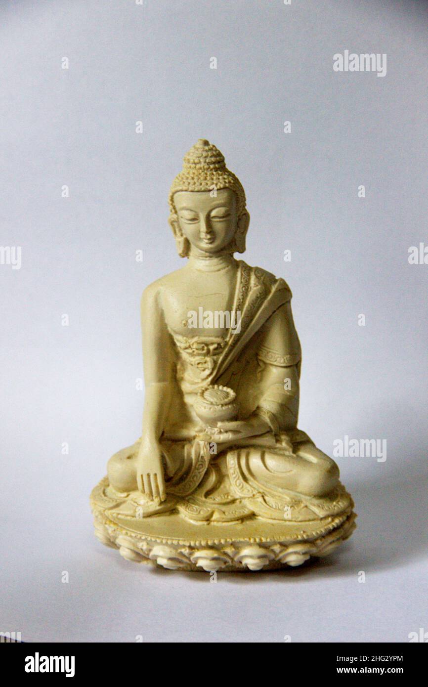 Painted, plaster icon of Buddha in composed, sitting position in white background Stock Photo