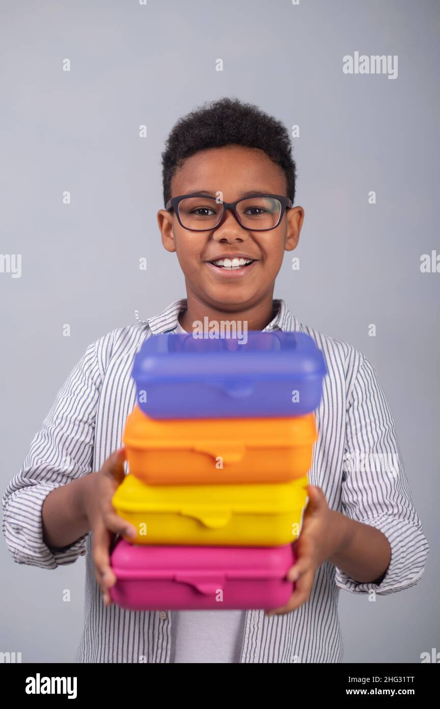 Joyful boy holding closed food containers in his hands Stock Photo