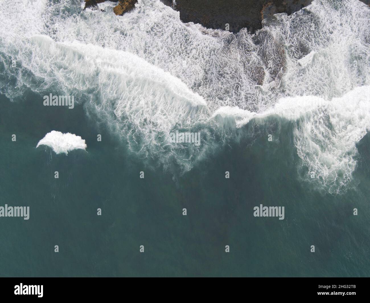 Top down aerial view of giant ocean waves crashing and foaming in coral ...