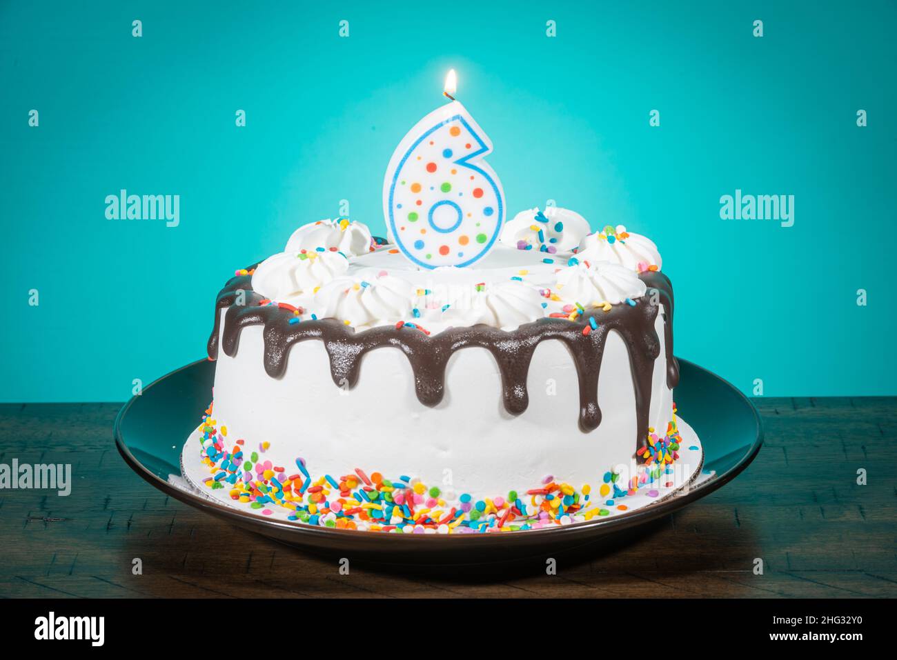 A birthday cake bears a candle in the shape of the number 6. Stock Photo