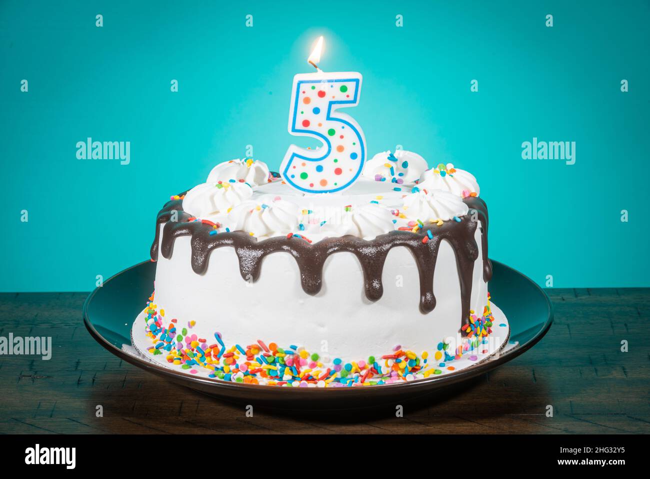 A birthday cake bears a candle in the shape of the number 5. Stock Photo