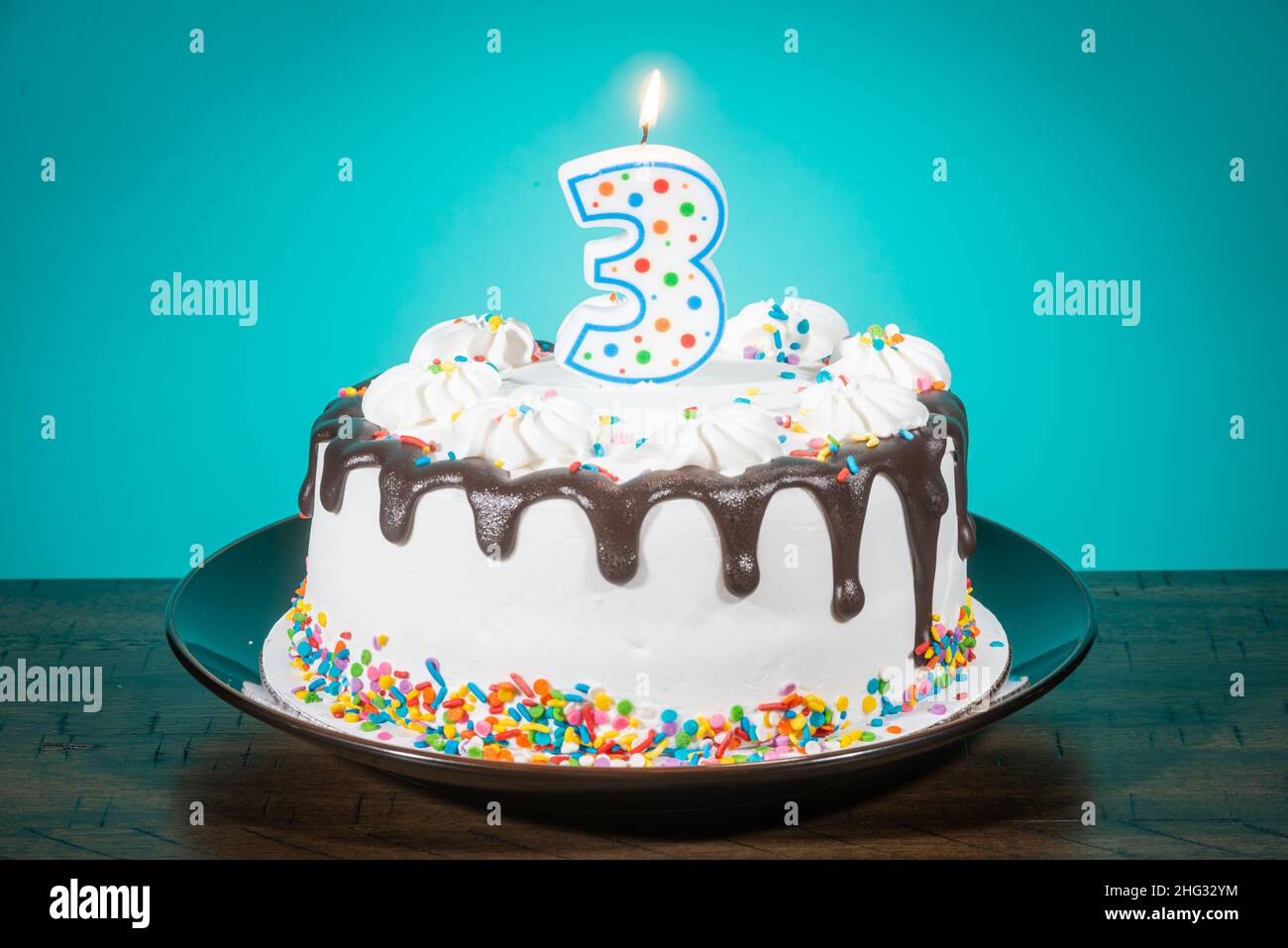 A birthday cake bears a candle in the shape of the number 3. Stock Photo