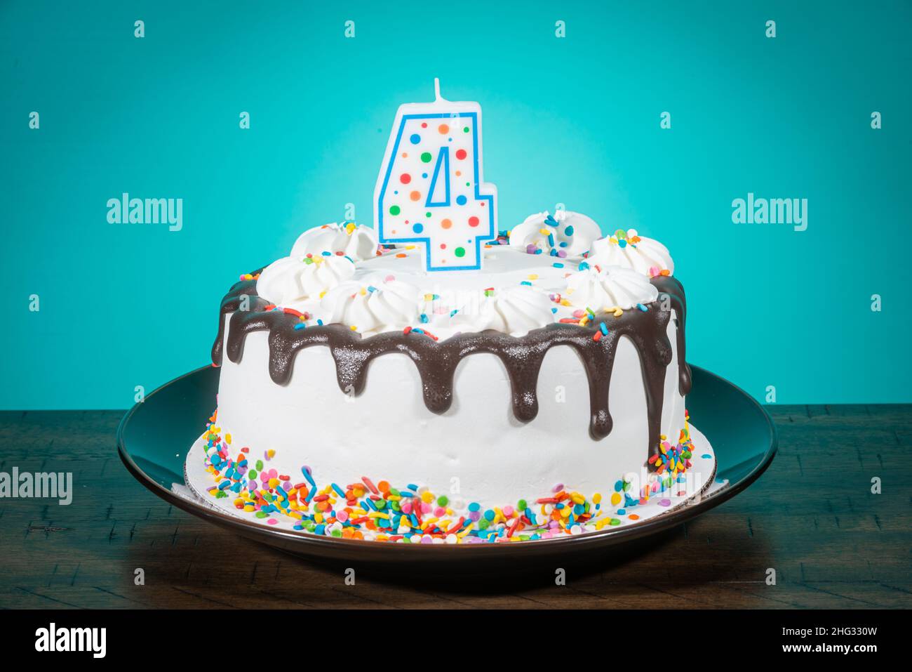 A birthday cake bears a candle in the shape of the number 4. Stock Photo