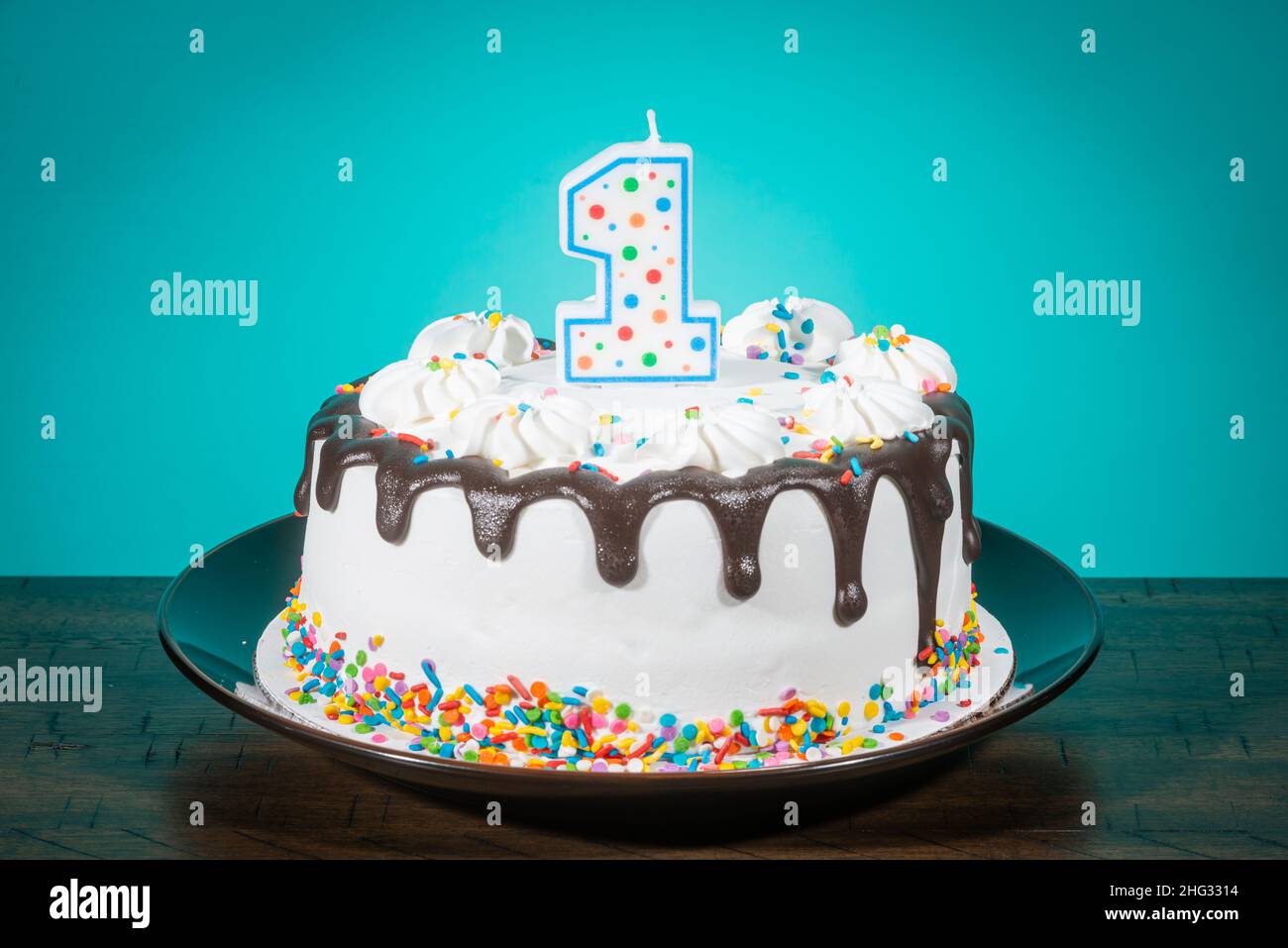 A birthday cake bears a candle in the shape of the number 1. Stock Photo