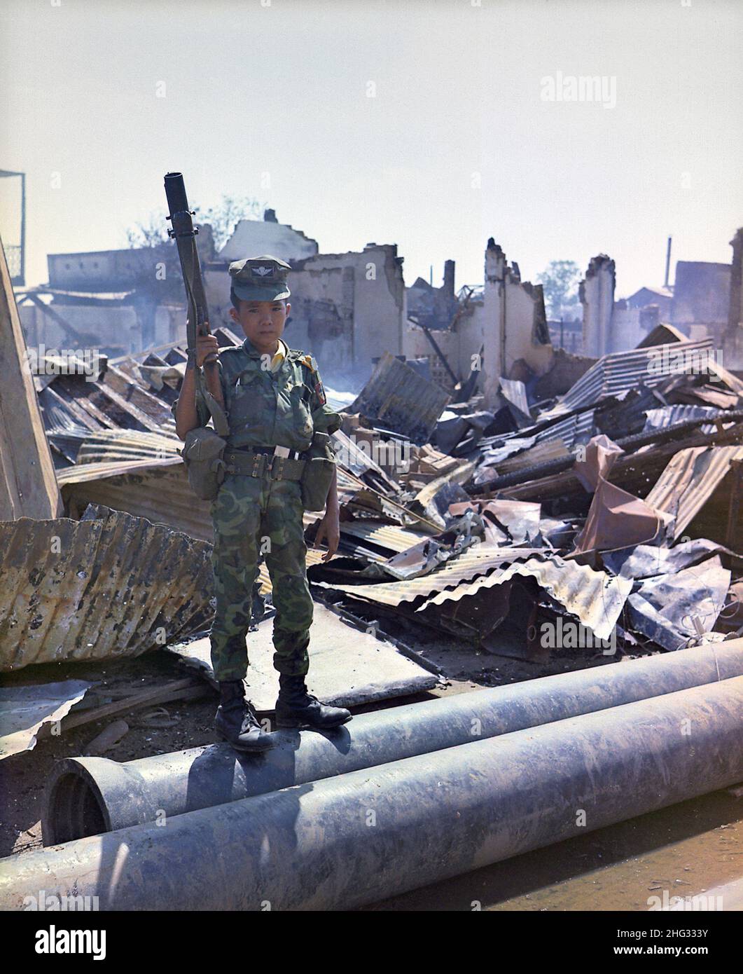 A Vietnamese child soldier in 1968. This twelve year old ARVN Airborne trooper with M-79 grenade launcher accompanied the Airborne Task Force Unit on a sweep through the devastated area surrounding the French National Cemetery on Plantation Road after a day long battle there. The young soldier has been 'adopted' by the Airborne Division. Stock Photo