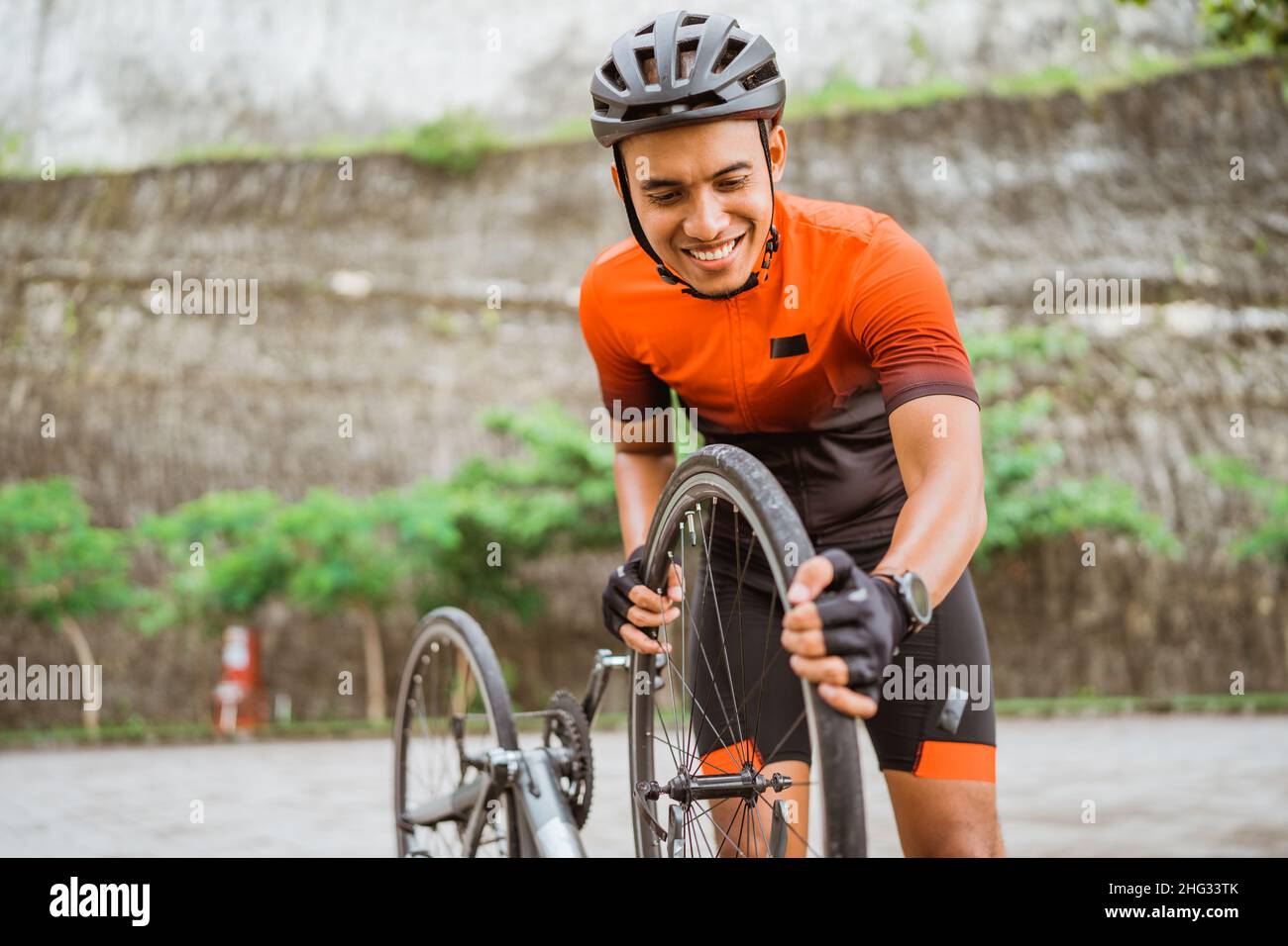 asian male cyclist checking his road bike tire Stock Photo - Alamy