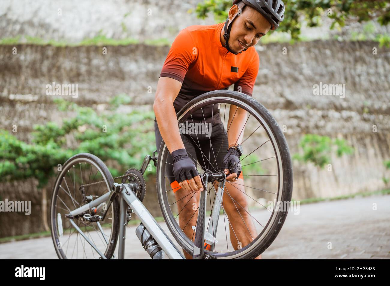 asian male cyclist checking his road bike tire Stock Photo - Alamy