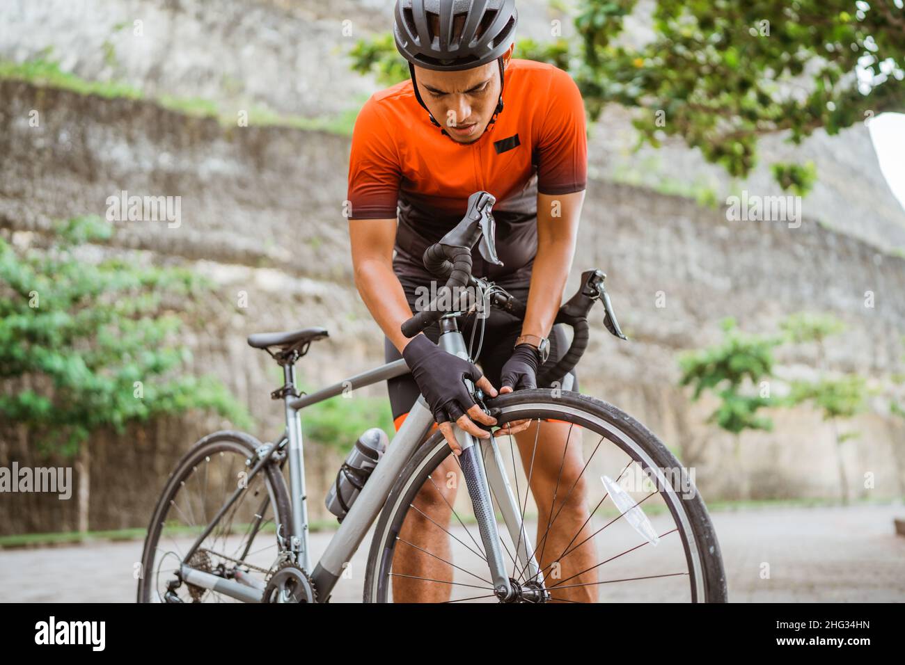 asian male cyclist checking his road bike tire Stock Photo - Alamy