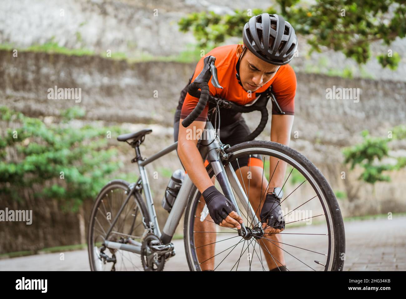 asian male cyclist checking his road bike tire Stock Photo - Alamy