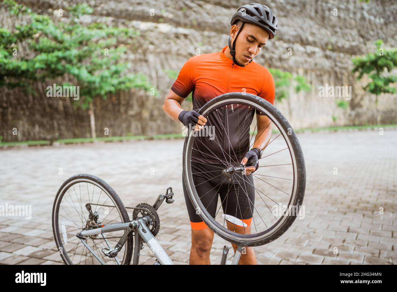 asian male cyclist checking his road bike tire Stock Photo - Alamy