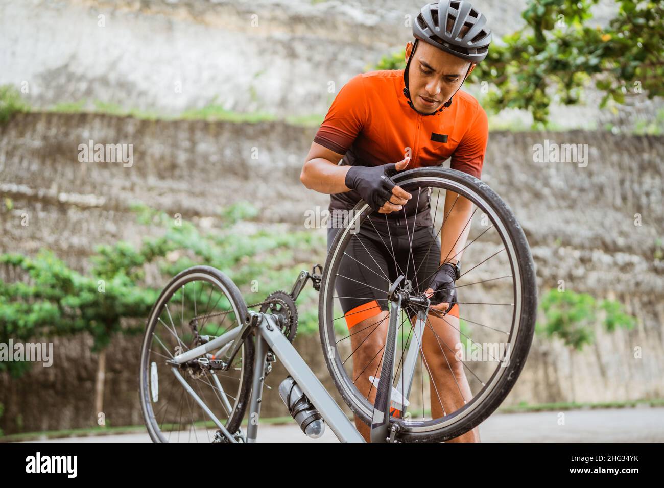 asian male cyclist checking his road bike tire Stock Photo - Alamy