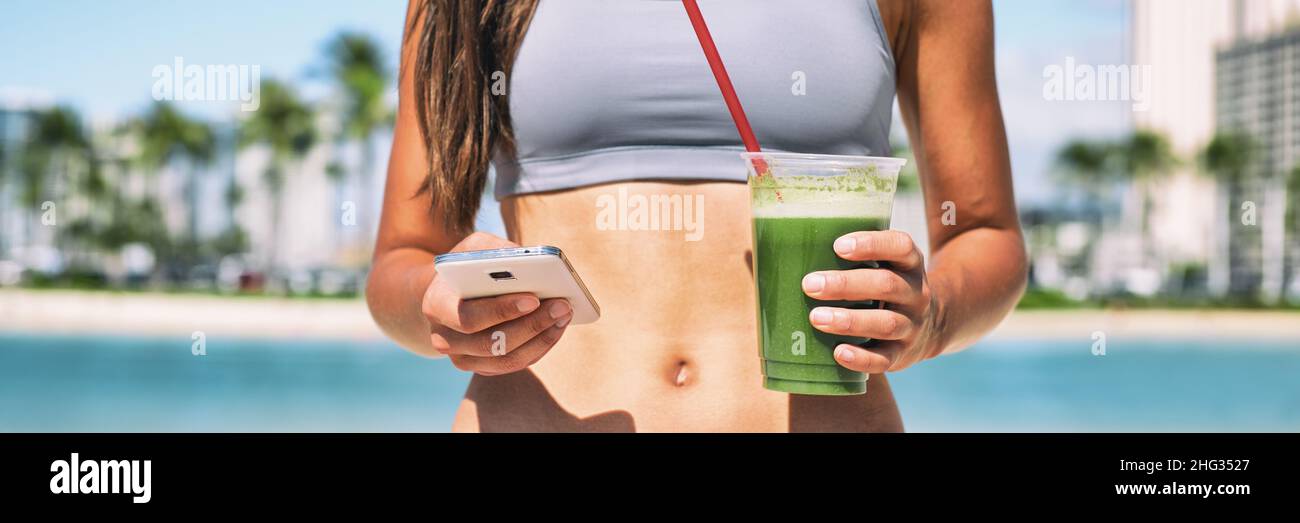 Green smoothie juice cleanse online phone app fitness diet plan banner panoramic. Woman stomach closeup with hands holding cup and mobile cellphone Stock Photo