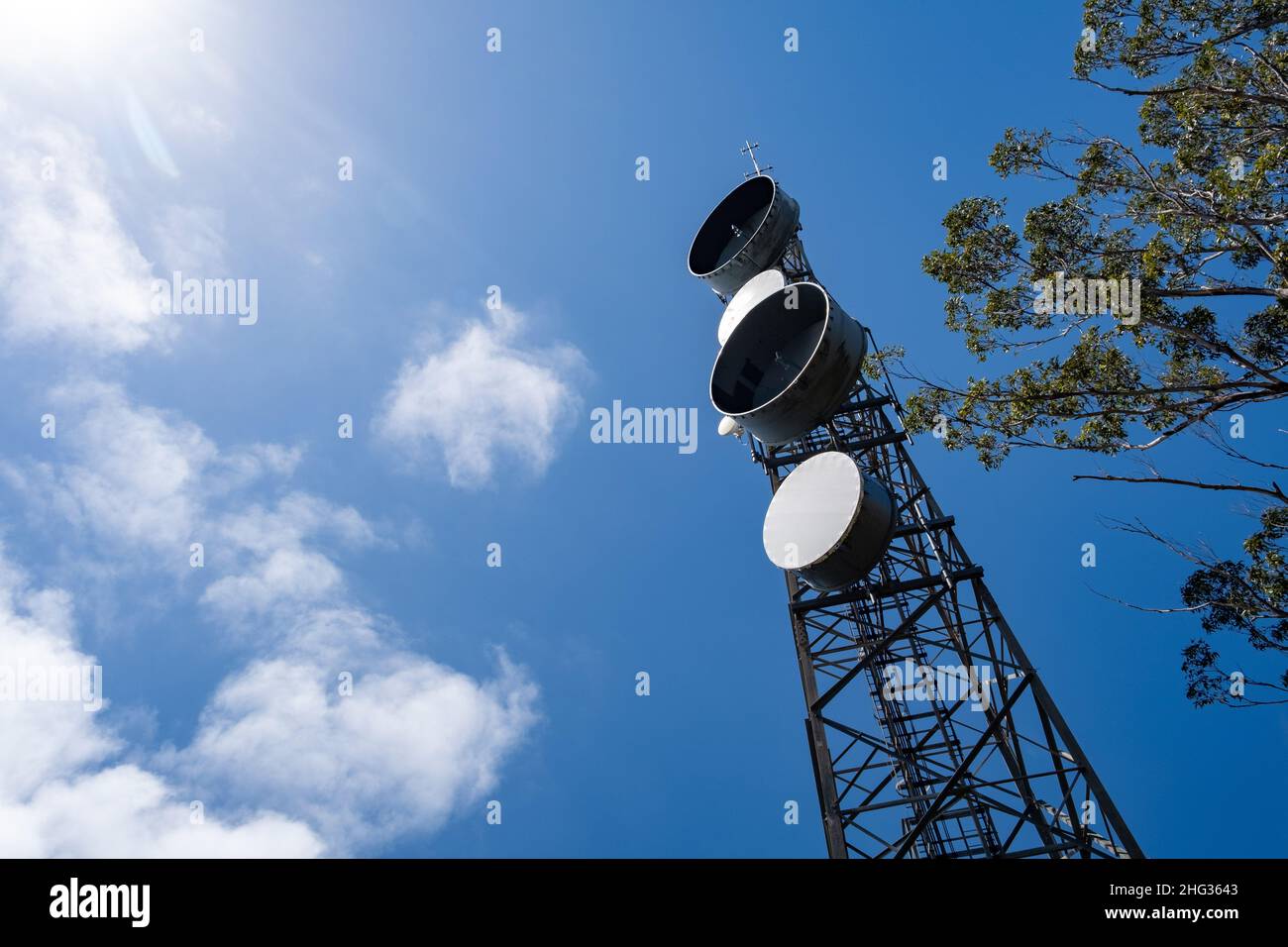 Looking up at telecommunications tower against blue sky with copy space Stock Photo