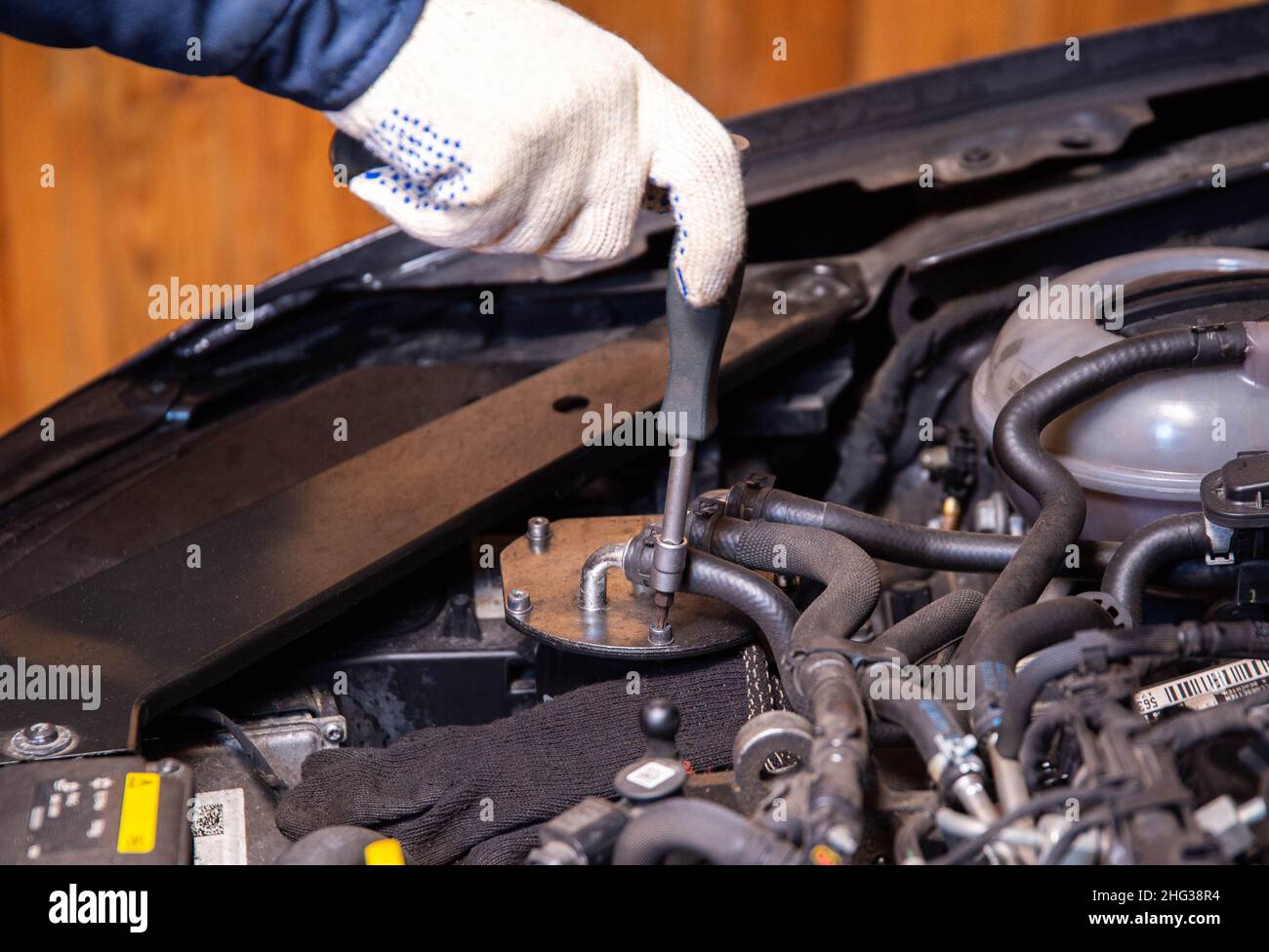 The mechanic unscrews the fuel filter flask for replacement. Car