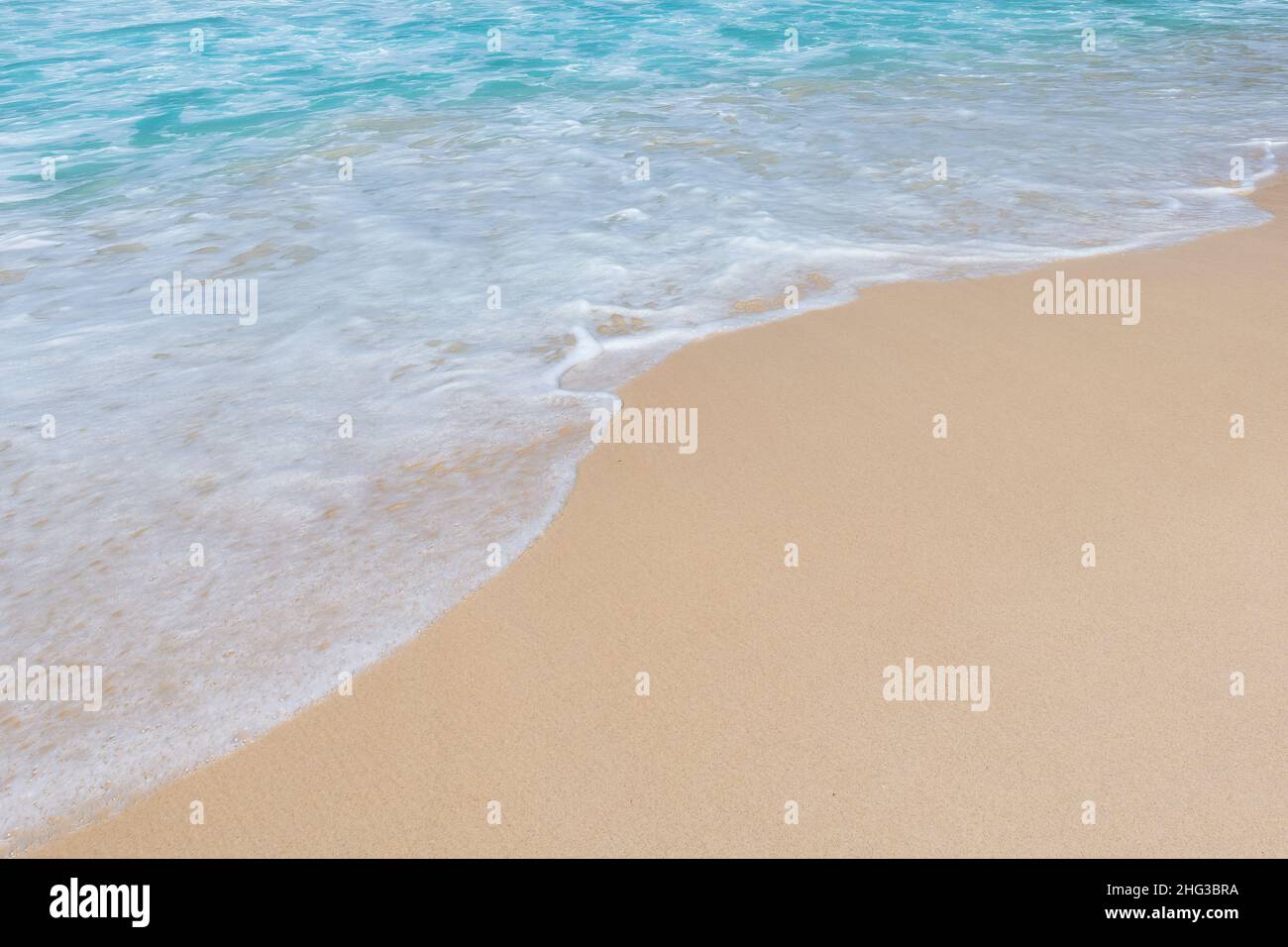 Soft ocean wave on clean sandy beach background Stock Photo