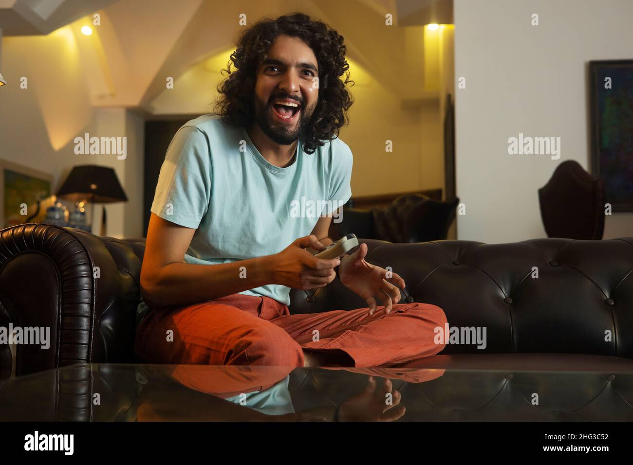 Man with curly hair watching sports on television and cheering Stock Photo