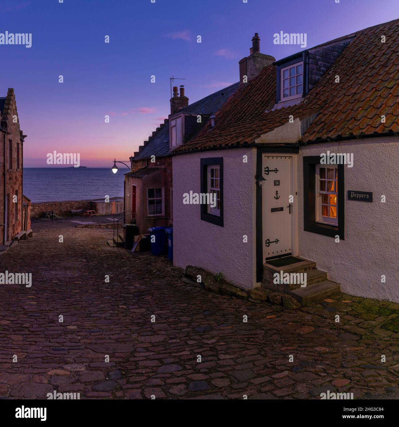 A view down a cobbled street, looking out towards the Isle of May in the River Forth, in the East Neuk village of Crail, Fife, Scotland Stock Photo