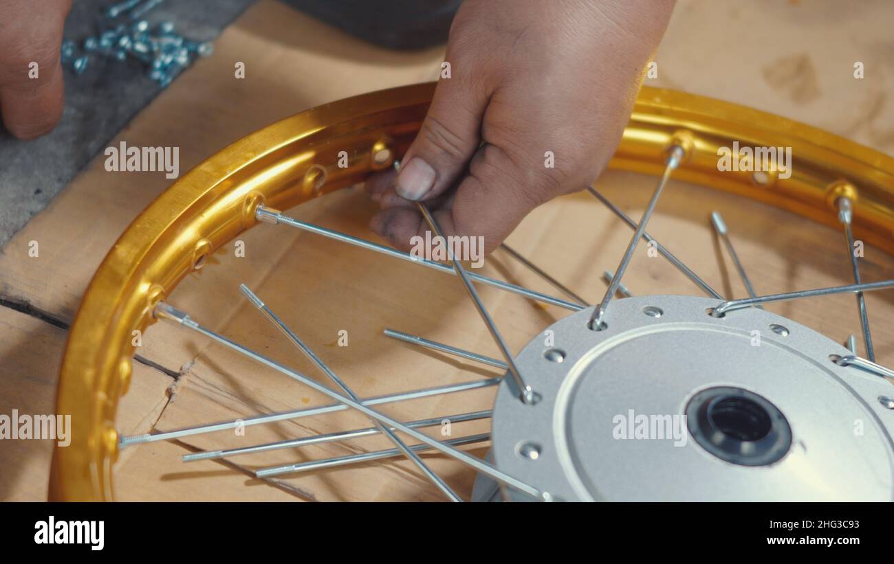Technician man working motorcycle wheel has spokes weave up on mechanic