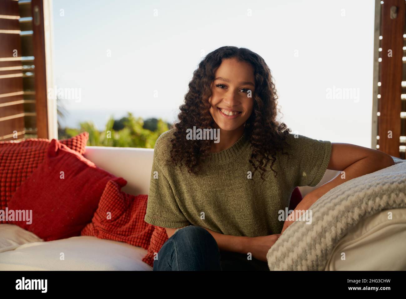 African American female smiling while sitting on sofa  Stock Photo