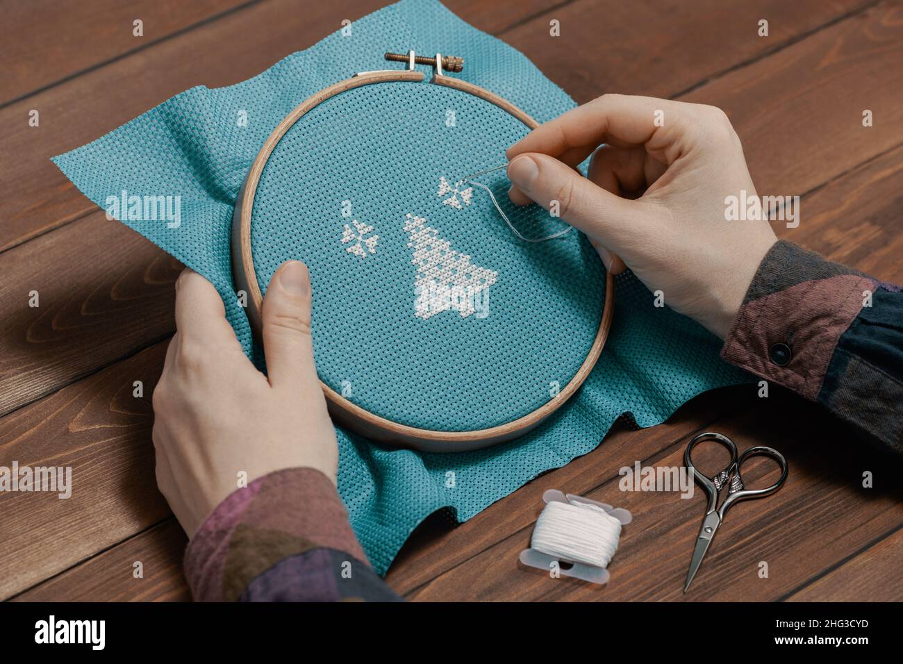 Woman making stitch on canvas and embroidering pattern. Stock Photo