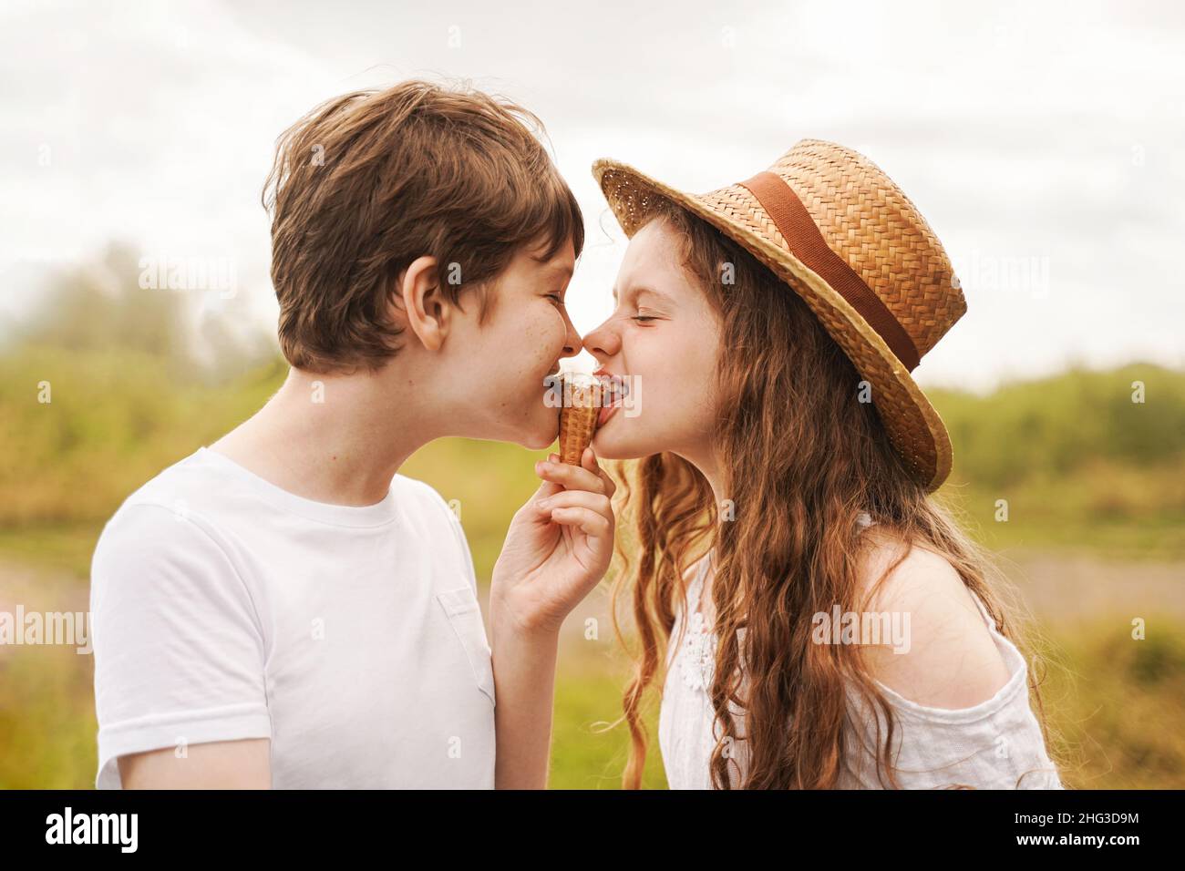 Children eat ice cream outdoors. Brothers and sister laugh and eat ice cream in the village in summer. Stock Photo