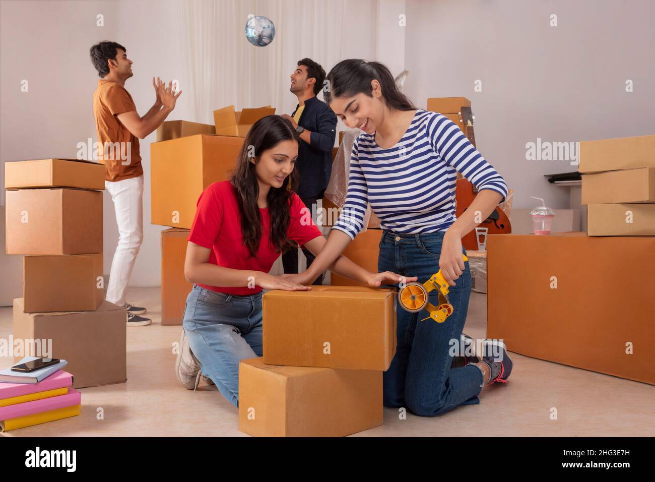 Girls packing cardboard boxes and the boys playing ball Stock Photo - Alamy