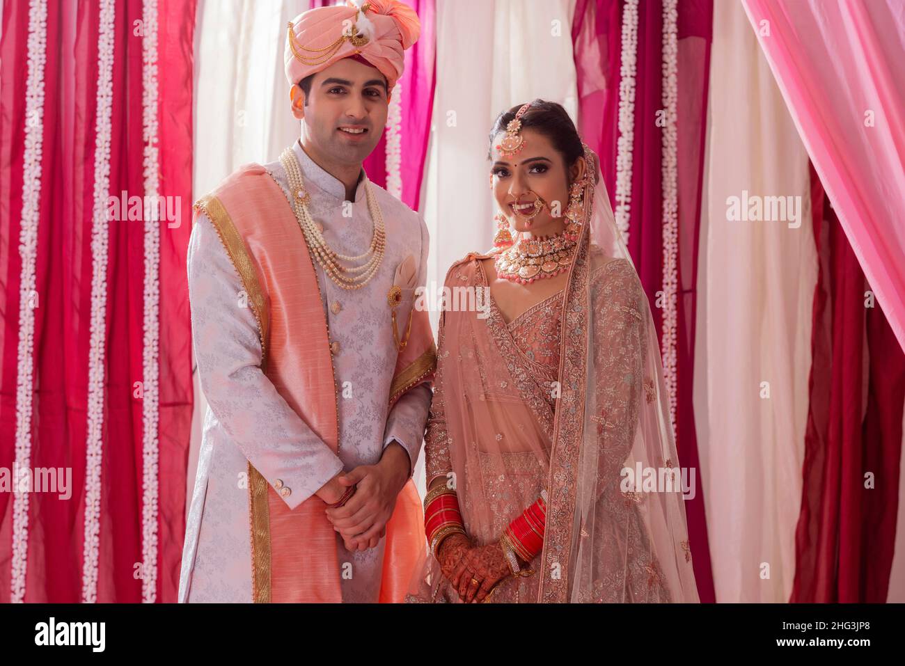 Portrait of an Indian wedding couple posing in front of camera during ...