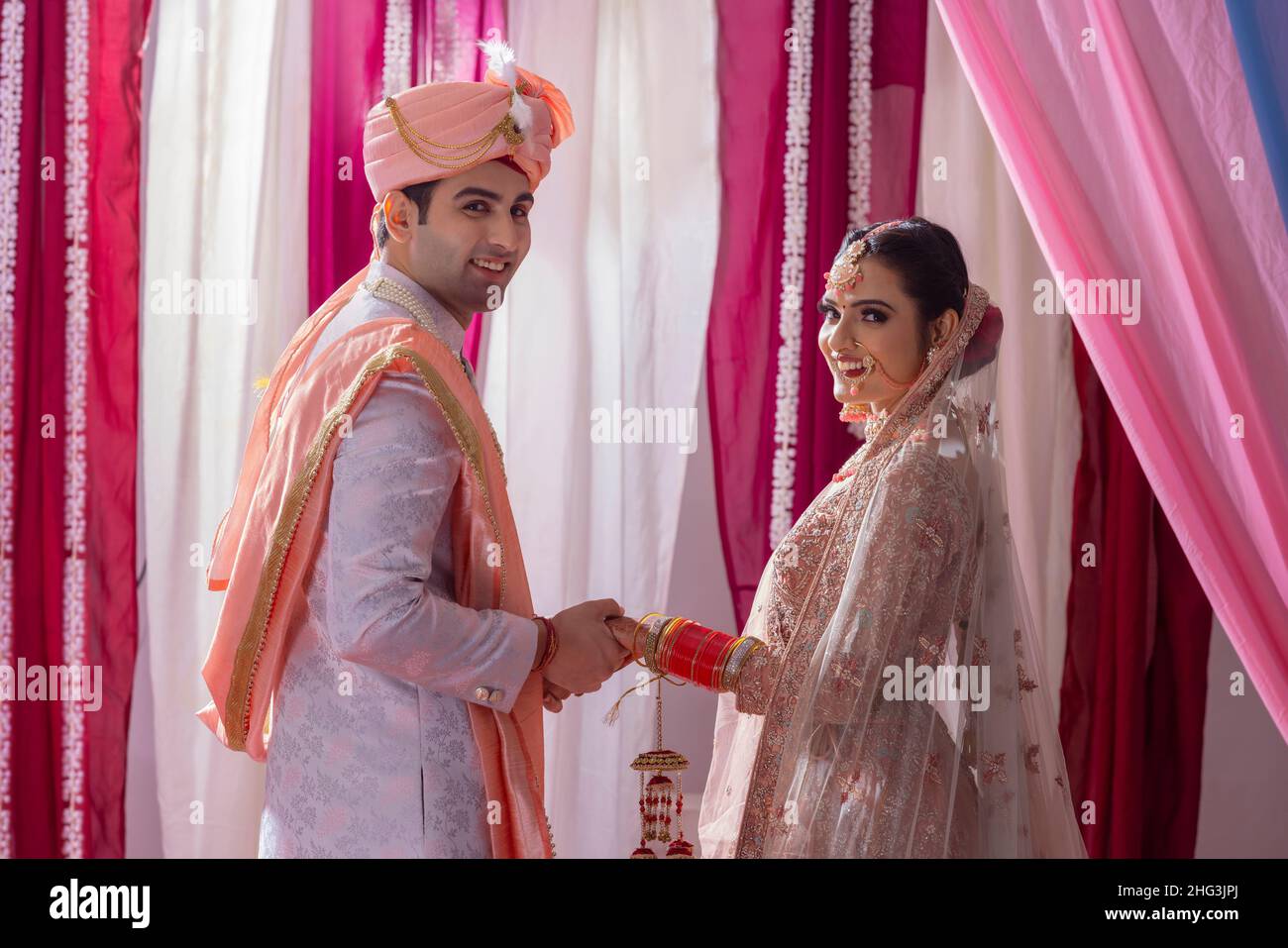 Portrait of an Indian wedding couple posing in front of camera during ...