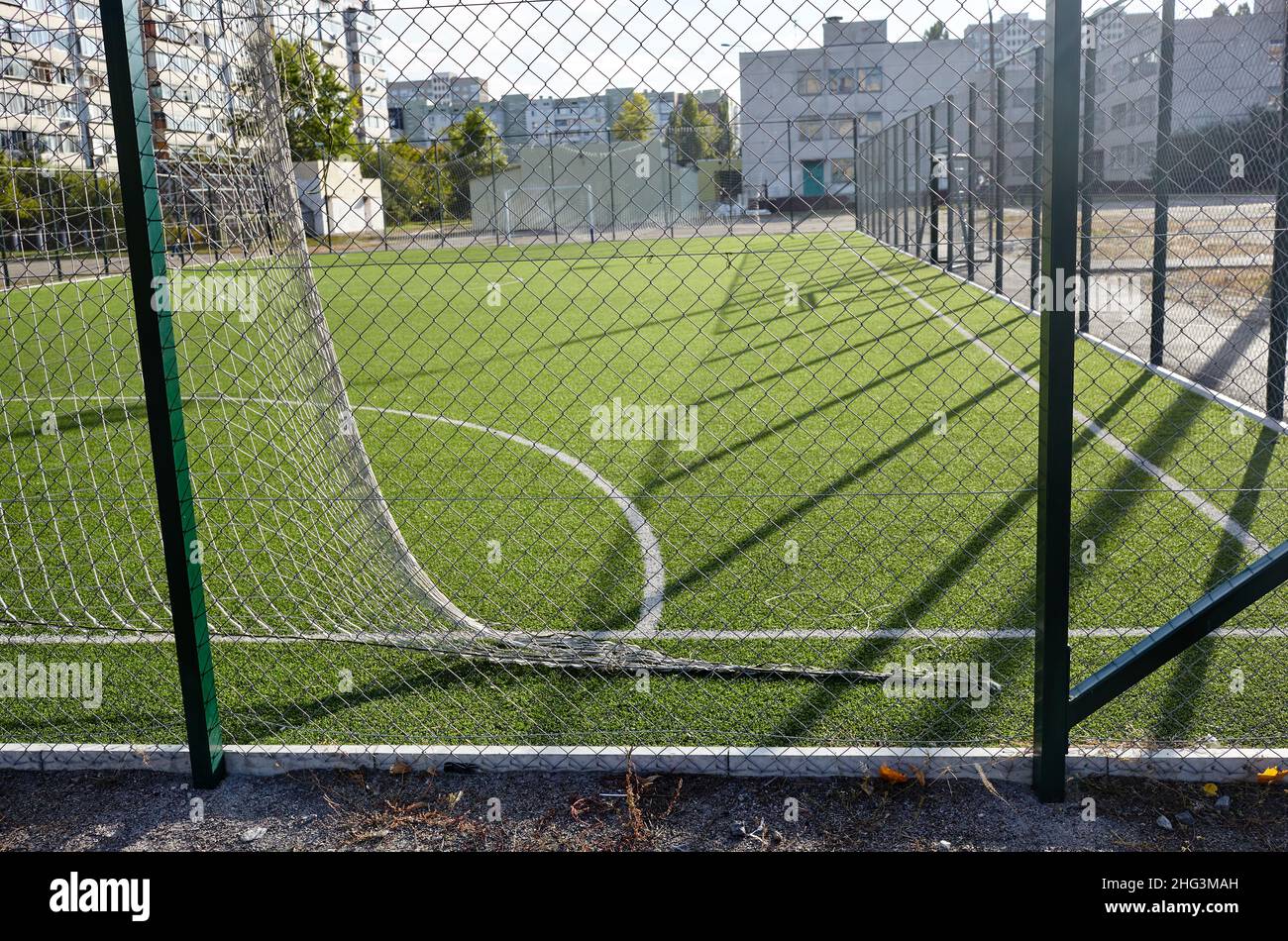 Lawn field for playing football behind the green fence mesh. Close-up of soccer field with green grass Stock Photo