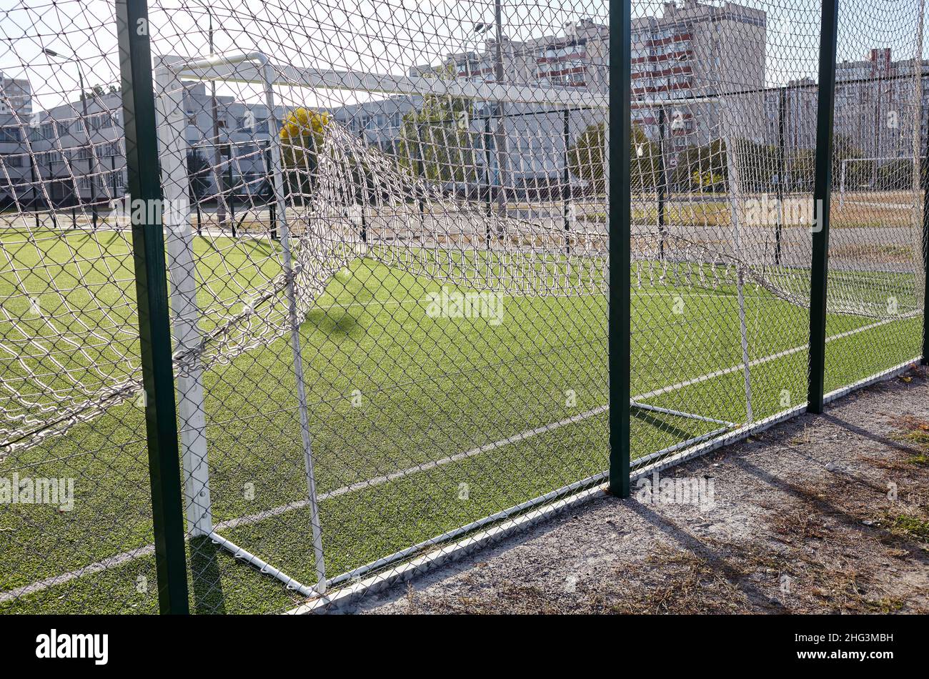 Lawn field for playing football behind the green fence mesh. Close-up of soccer field with green grass Stock Photo