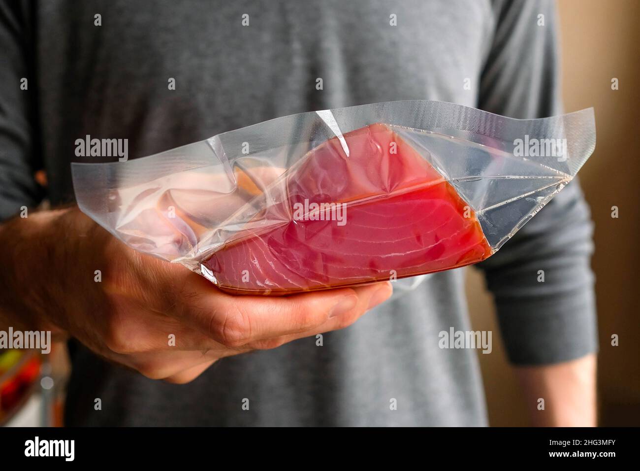 Holds a piece of tuna in a package in his hand. Stock Photo