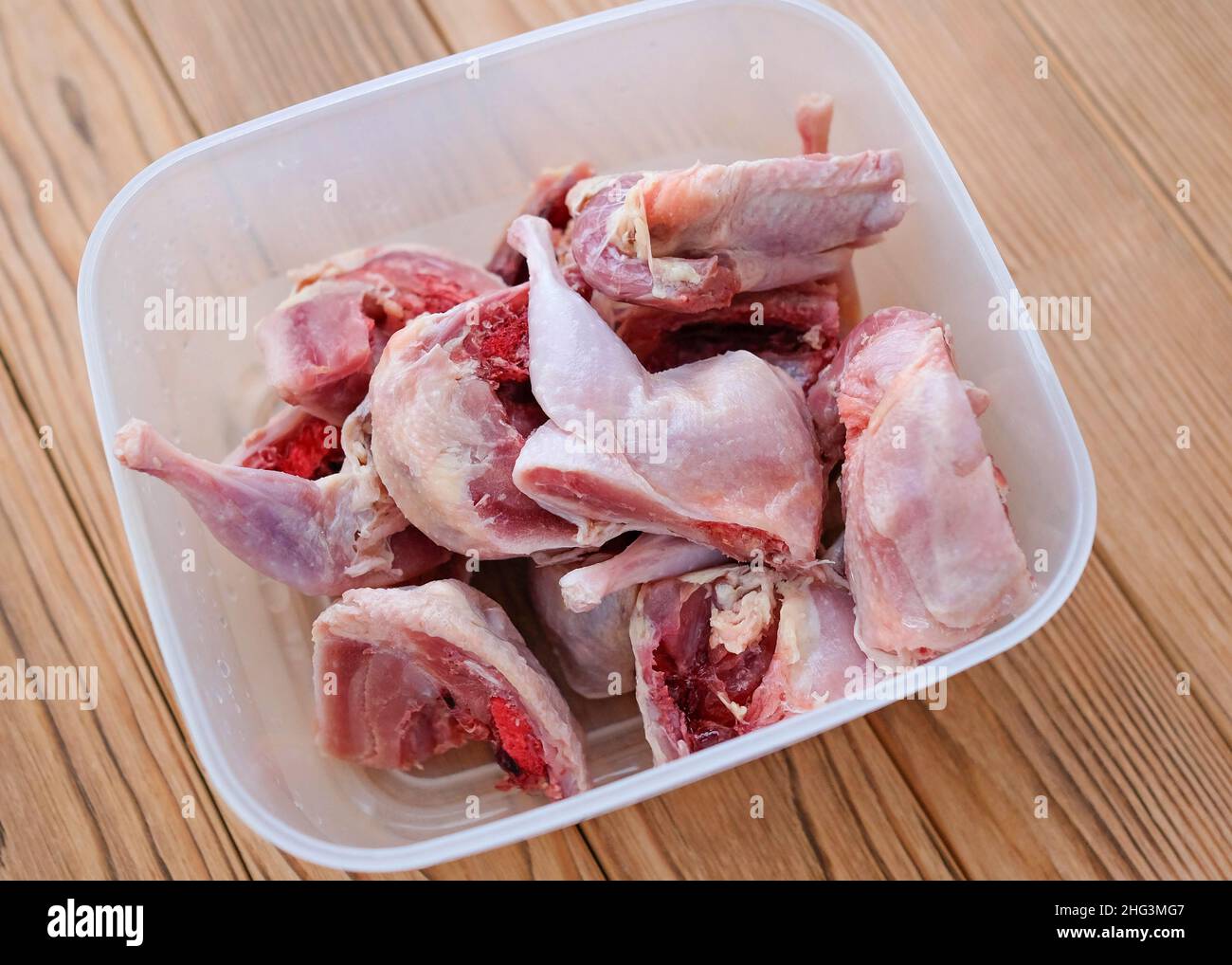 Quail cut into large pieces in a container. Freezing food for a cat. Stock Photo