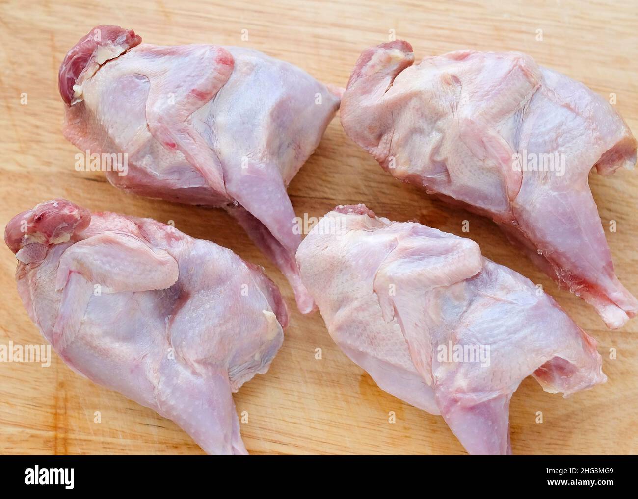 Quail carcasses lie on a cutting board. Small birds are prepared for cooking. Stock Photo