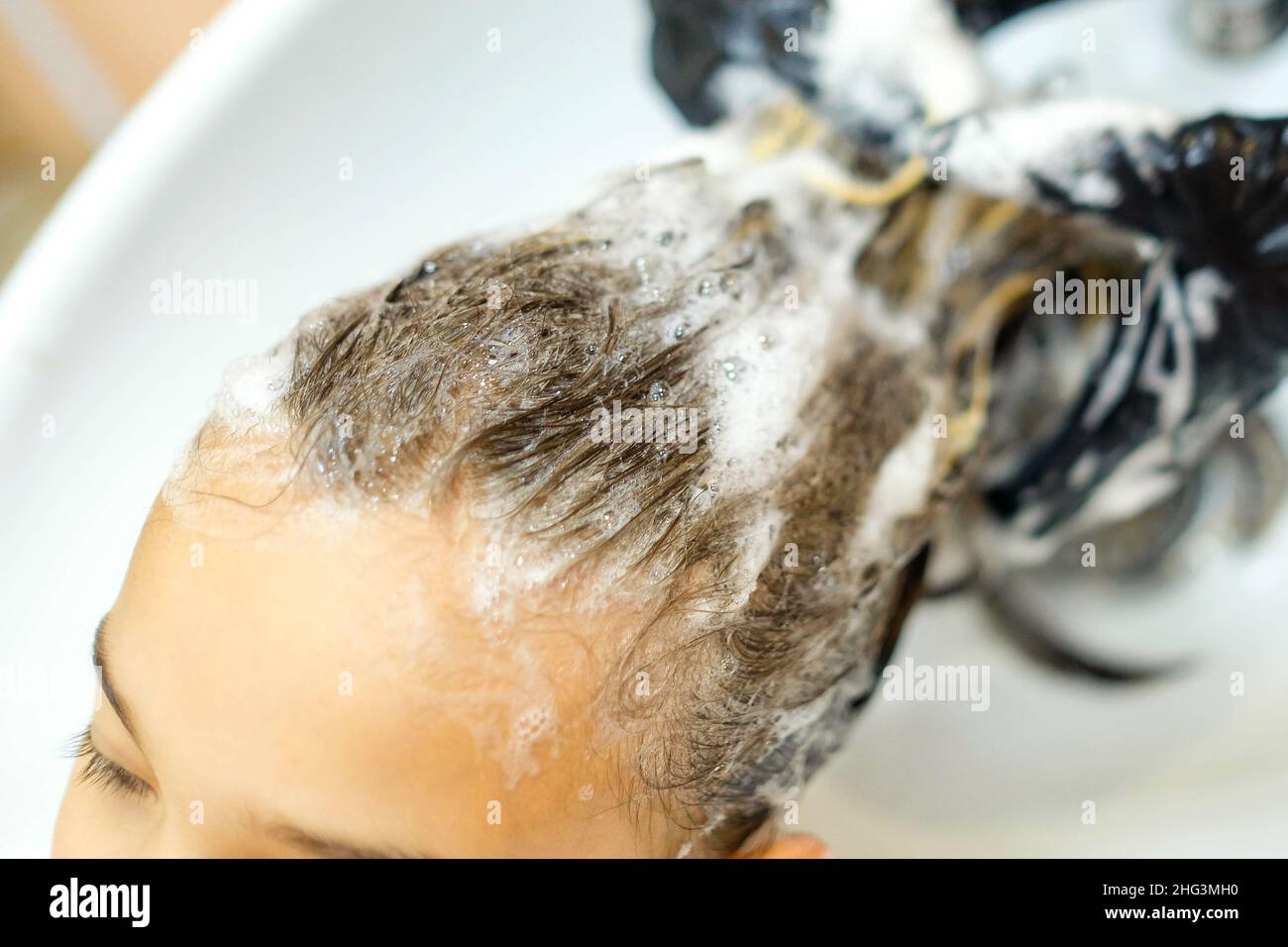 The girl is washed her hair in the salon. Shampoo bubbles close up. Stock Photo