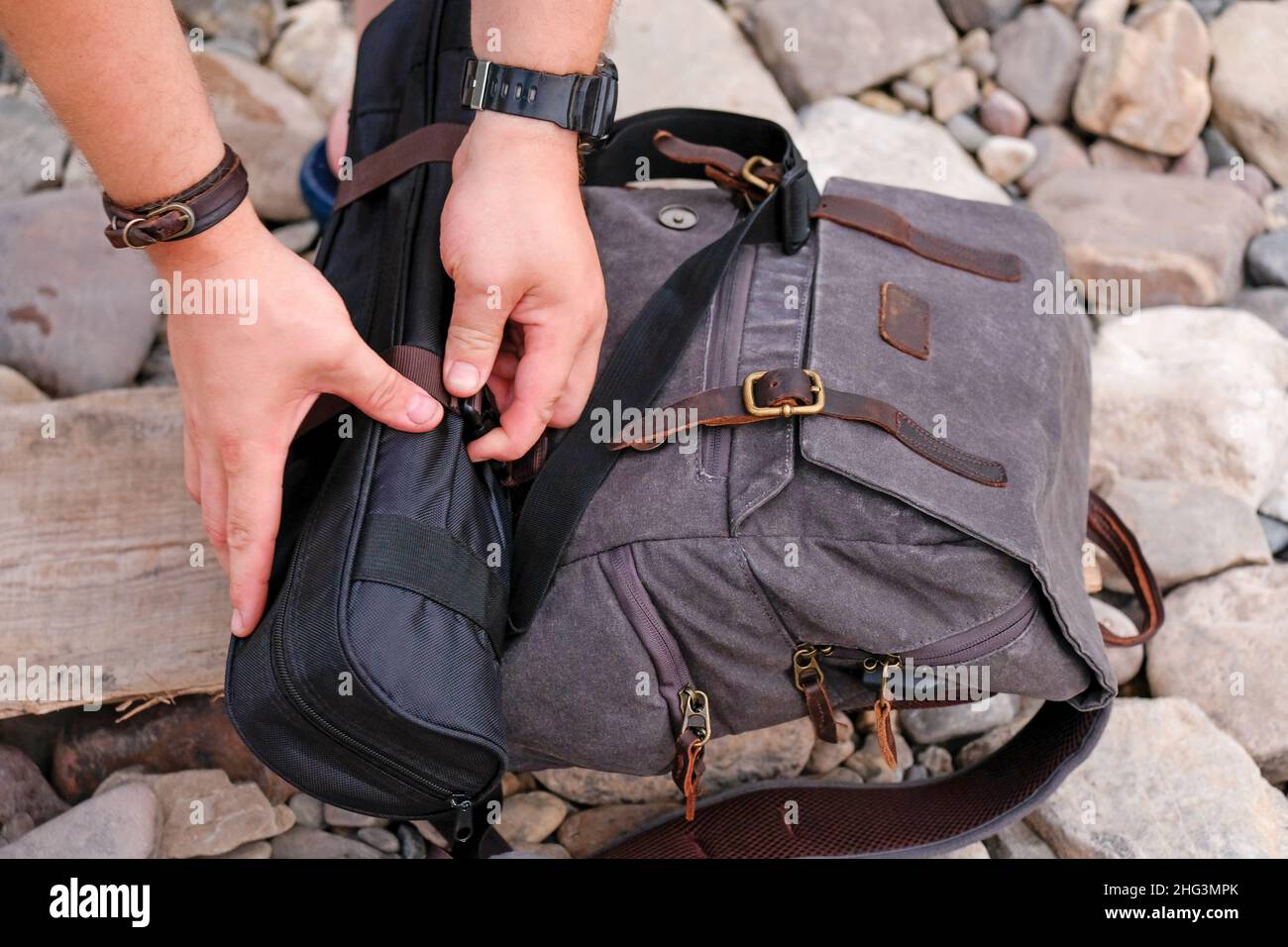 Collect a backpack on the banks of the river, on the stones. Hands visible. Stock Photo