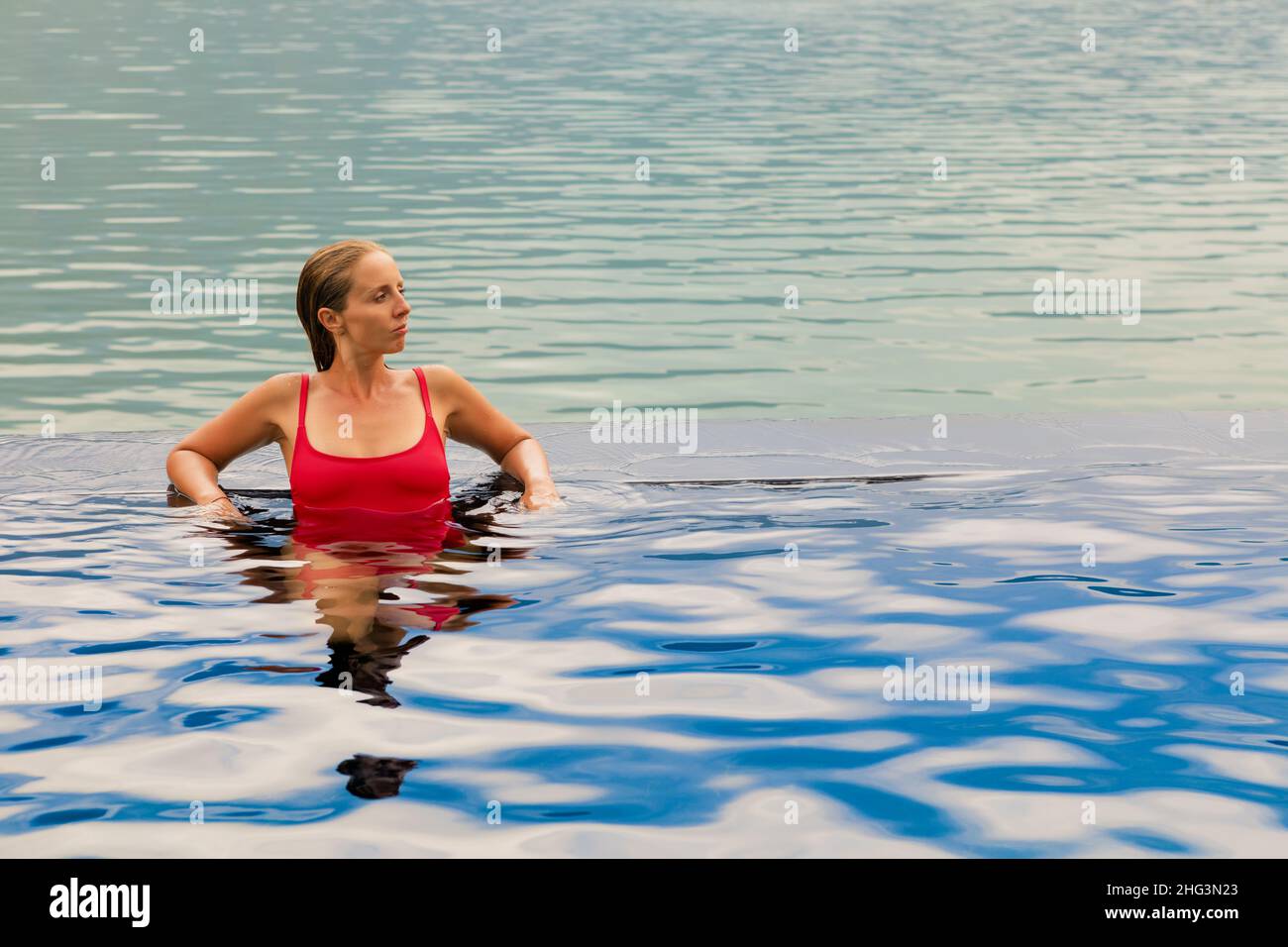 Young woman relax in infinity pool with lake view. Natural hot spring spa under Batur volcano. Travel in Kintamani, Bali. Healthy lifestyle Stock Photo