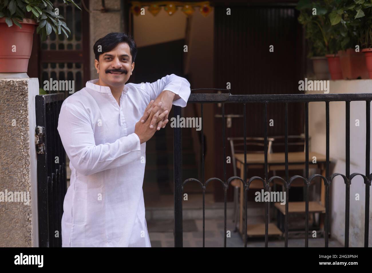 Middle age man in white kurta standing at entrance gate in the morning Stock Photo