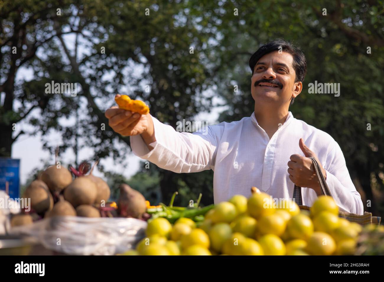 Man in white kurta shopping ginger in market Stock Photo