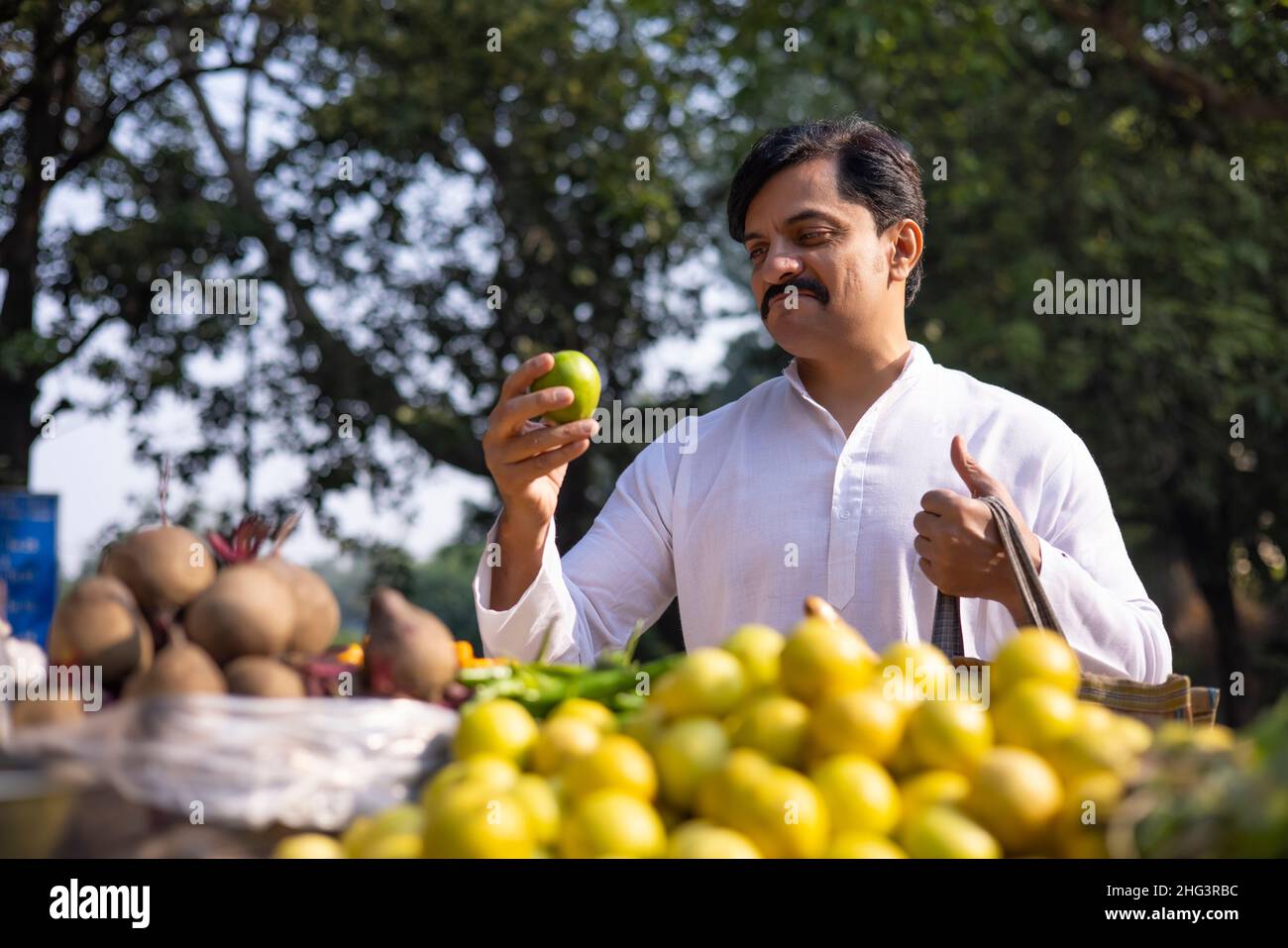 Man in white kurta shopping lemon in market Stock Photo